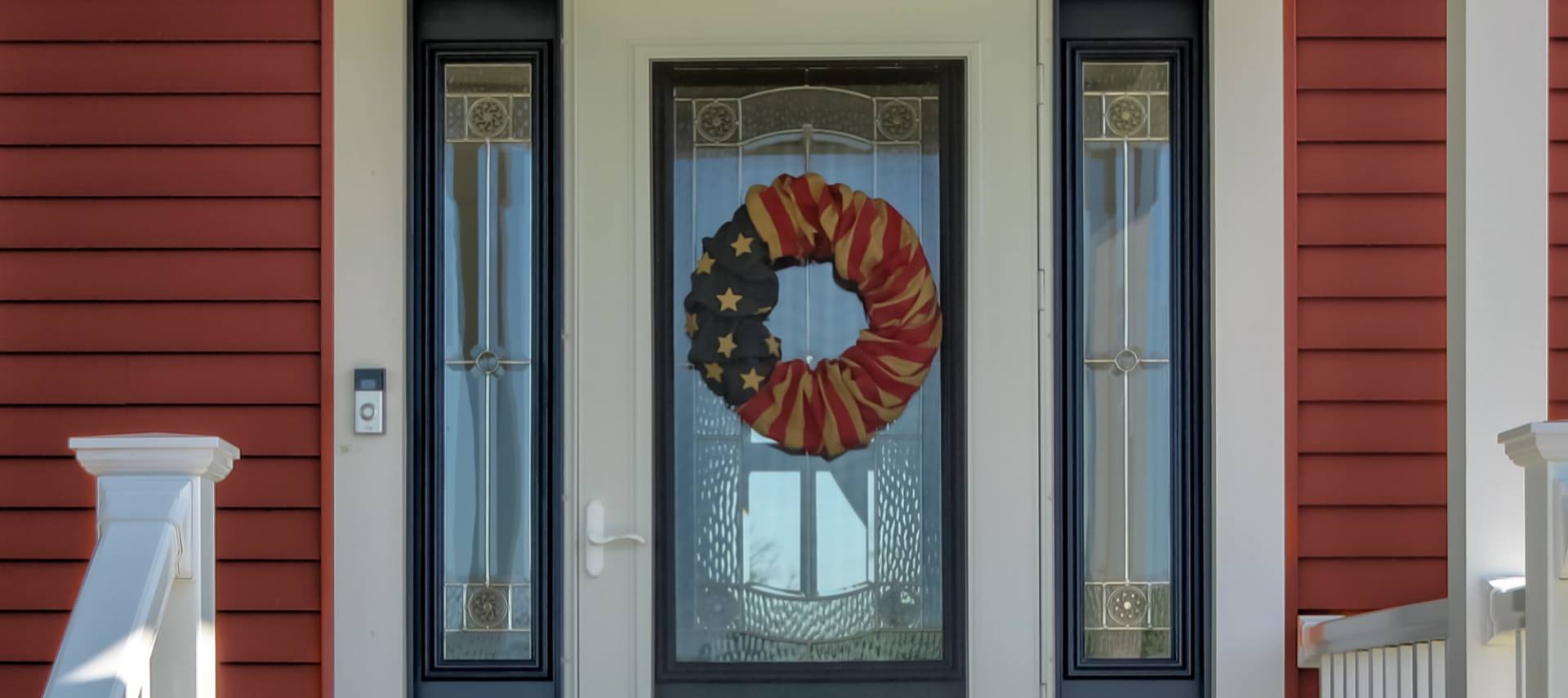 Exterior view of property's front door painted white with navy trim and wreath decorated with American flag fabric
